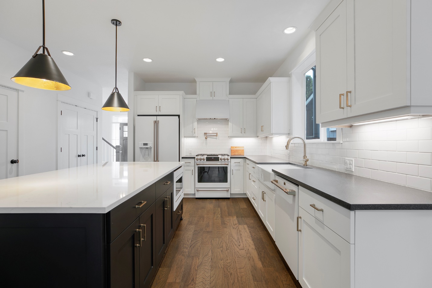 Kitchen with black and white cabinetry, gold hardware and a large center island